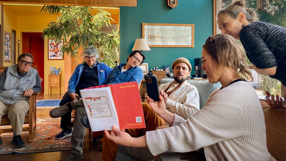 Small group gathered in a cozy living room, sharing stories and looking at a book.